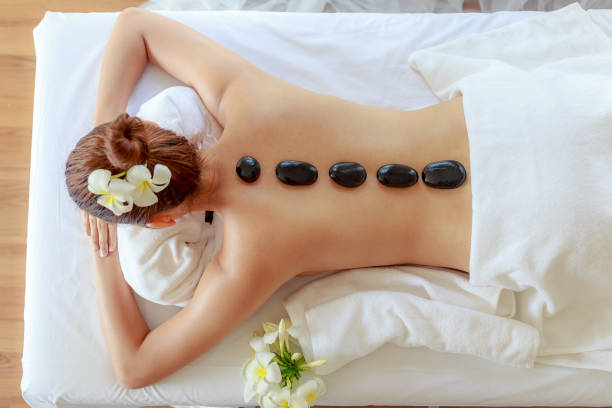Piedras volcánicas colocadas sobre la espalda de una persona en un ambiente de spa en Quironatura Torrox, transmitiendo calor terapéutico para relajar los músculos y aliviar tensiones.